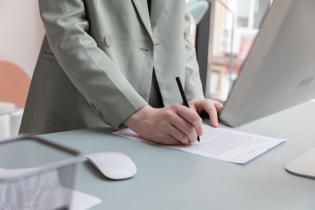 someone standing at a desk writing on paper